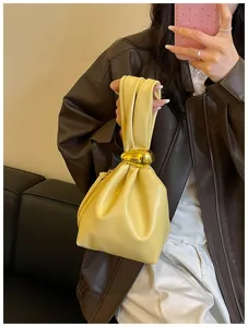 Nahaufnahme einer modischen plissierten gelben Handtasche mit massivem Metallringgriff.