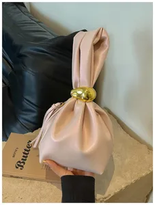Nahaufnahme einer stylischen rosa Raffhandtasche mit goldenem Ring auf Steindisplay.