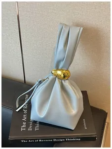 Nahaufnahme der hellblauen Faltenhandtasche mit dem einzigartigen goldenen Ringgriff-Detail.