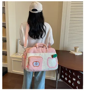 Detail of the pink large capacity casual travel bag with apple patch and dual straps.
