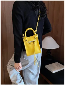 Sac bandoulière mini moto jaune avec clous et poignée supérieure pour le style quotidien.