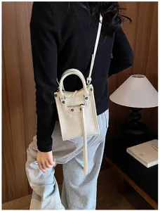 Petit sac bandoulière moto vertical blanc avec rivets et poche zippée pour femmes élégantes.