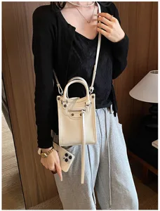 Vue de détail du petit sac bandoulière moto blanc, design clouté élégant, parfait pour l'été.