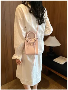 Sac bandoulière moto chic en cuir rose avec rivets et glands pour la mode des femmes.