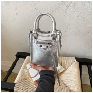 Détail de mini sac de téléphone moto argenté métallique avec rivets et poche zippée.