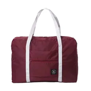 Foldable large capacity travel duffel bag in burgundy with white straps and front pocket.