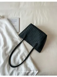 Black woven tote bag detail showing intricate texture, premium craftsmanship and twin straps.
