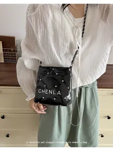 Trendy black quilted crossbody bag with metal chain and chic rhinestone stud details.