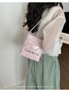 Detail view of stylish quilted shoulder bag with chain strap and metallic lettering in pink.