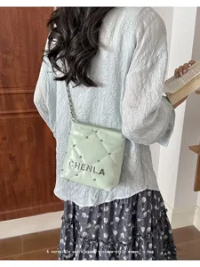 Light green quilted shoulder bag for women with metal chain strap and studs, stylish daily.