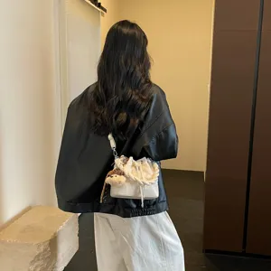 Stylish minimalist white bucket shoulder bag for women, chic crossbody design with charm.