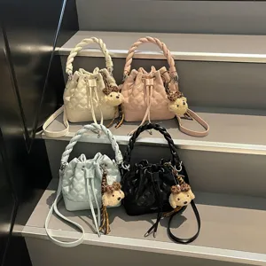 Stylish quilted bucket shoulder bag for women with braided top handle and plush bear charm.