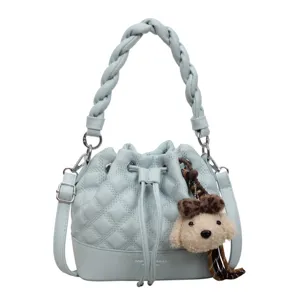 Light blue quilted bucket bag with braided handle and cute plush dog charm for women.