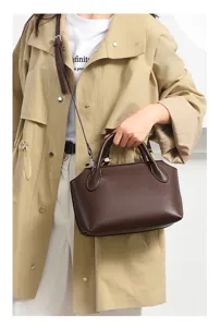 Detailed view of dark brown retro leather bowling handbag, chic commuter crossbody bag.