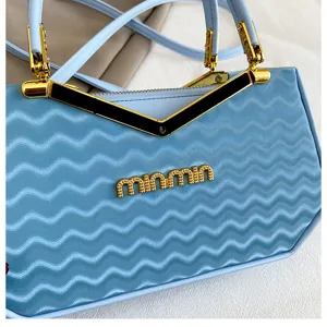 Borsa a mano alla moda azzurro chiaro con motivo a onde, finiture oro e dettagli in metallo.