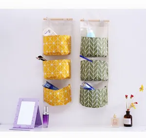 Detail view of cotton linen hanging storage bag with three pockets for dorm room organization.