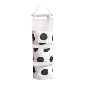 Wall hanging storage bag with black polka dots, multi-pocket fabric organizer for bedroom.
