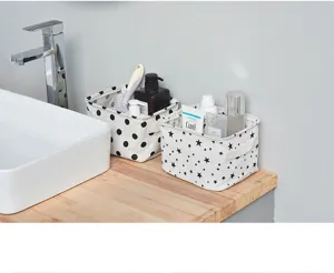 Close-up of cute polka dot and star fabric storage baskets on wooden countertop in bathroom.