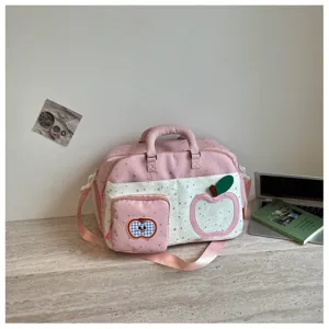 Close-up detail of the pink travel duffel bag featuring cute star patterns and apple patches.