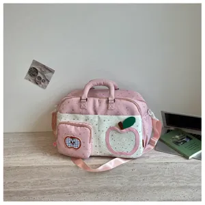 Detail view of pink star pattern travel duffel bag with cute apple patch and crossbody strap.