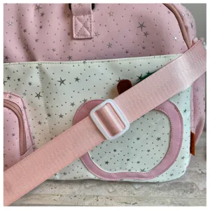 Close up detail of pink travel duffel bag with star pattern and cute apple pocket design.