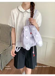 Vue détaillée du joli sac à dos en toile violette avec écussons d'étoiles et design doux.