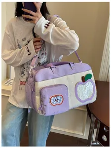 Purple canvas travel duffel bag detail with cute apple patch and star print for daily use.