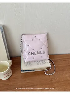 Close-up detail of the pink quilted shoulder bag with chain strap and metal letters charm.
