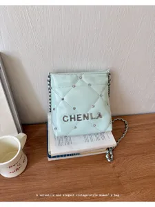 Detailed view of light green quilted crossbody bag with sparkling rhinestones and metal chain.