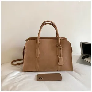 Detail view of retro brown suede Boston handbag, casual tote shoulder crossbody bag setting.