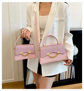 Close-up view of pink glitter square handbag with gold chain detail, chic niche design.
