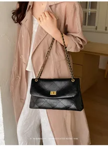Detailed view of black quilted leather shoulder bag with metal chain strap and turn lock.