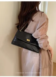 Women's black quilted shoulder bag with gold chain strap and turn-lock closure chic style.