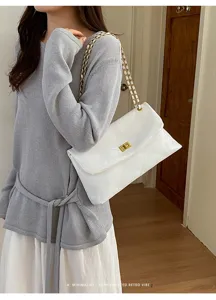 Minimalist white quilted shoulder bag detail, stylish gold chain and turn-lock clasp.