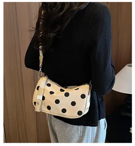 Gedetailleerd overzicht van een stijlvolle beige schoudertas met stippen, modieus.