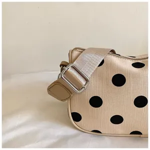 Gedetailleerd overzicht van modieuze schoudertas met polkadots, brede band en chique design.