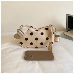 Gedetailleerd overzicht van de chique beige schoudertas met klassiek zwart stipjespatroon.