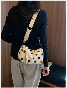 Gedetailleerd overzicht van de chique schoudertas met polkadots gedragen door het model.