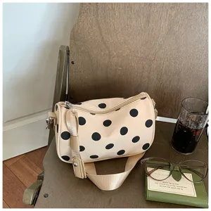 Gedetailleerd overzicht van de stijlvolle beige schoudertas met polka dot textuur.