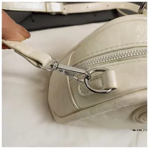 Witte gekreukte lederen schoudertas detail met zilveren hardware en gladde ritssluiting.