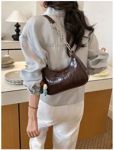 Detailed view of the dark brown crocodile-embossed underarm shoulder bag with a chunky chain.