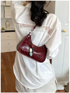 Detailed view of trendy wine red crocodile embossed hobo shoulder bag with cute beaded charm.