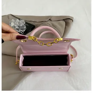 Pink PU leather small square bag detail, featuring top handle and elegant gold chain link decor.