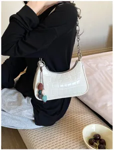 Detailed view of white crocodile pattern shoulder bag with chunky chain and cute beaded charm.