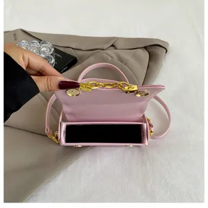 Detail view of the pink mini square handbag showing metal chain hardware and magnetic closure.