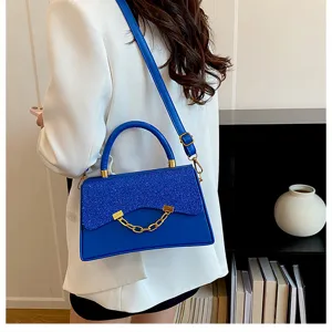Detailed view of the stylish royal blue crossbody bag with glitter flap and gold chain.