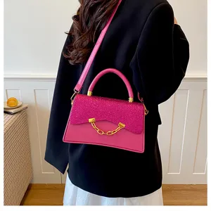 Pink glitter handbag detail showcasing the front flap, metal chain decor and sturdy handle.