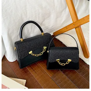 Close-up detail shot of stylish black glitter flap handbags with gold chain and top handle.