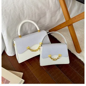 Detailed view of stylish white and glitter small square shoulder bag with gold chain decor.