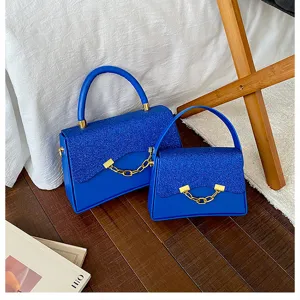 Detail blue glitter flap crossbody bag with chic gold chain detail and convenient top handle.